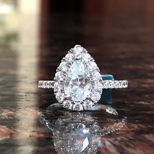 A pear shaped diamond ring is sitting on a table