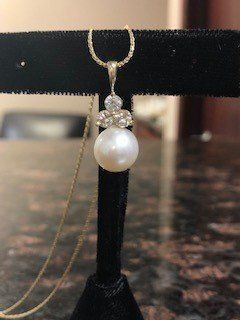 A close up of a pearl and diamond necklace on a display stand.