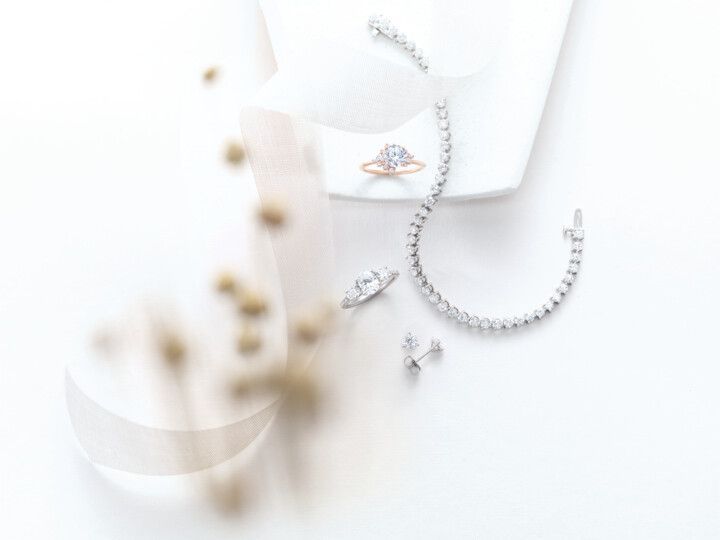 A close up of a necklace , earrings , and ring on a white surface.