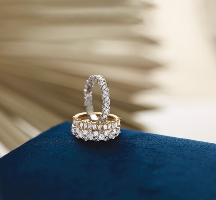 Two rings are stacked on top of each other on a blue pillow.