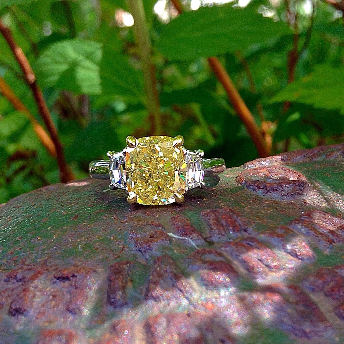 A yellow diamond ring is sitting on a rock