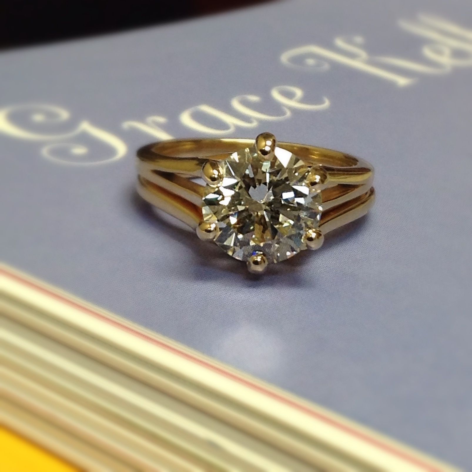 A diamond ring sits on top of a book titled grace kelly