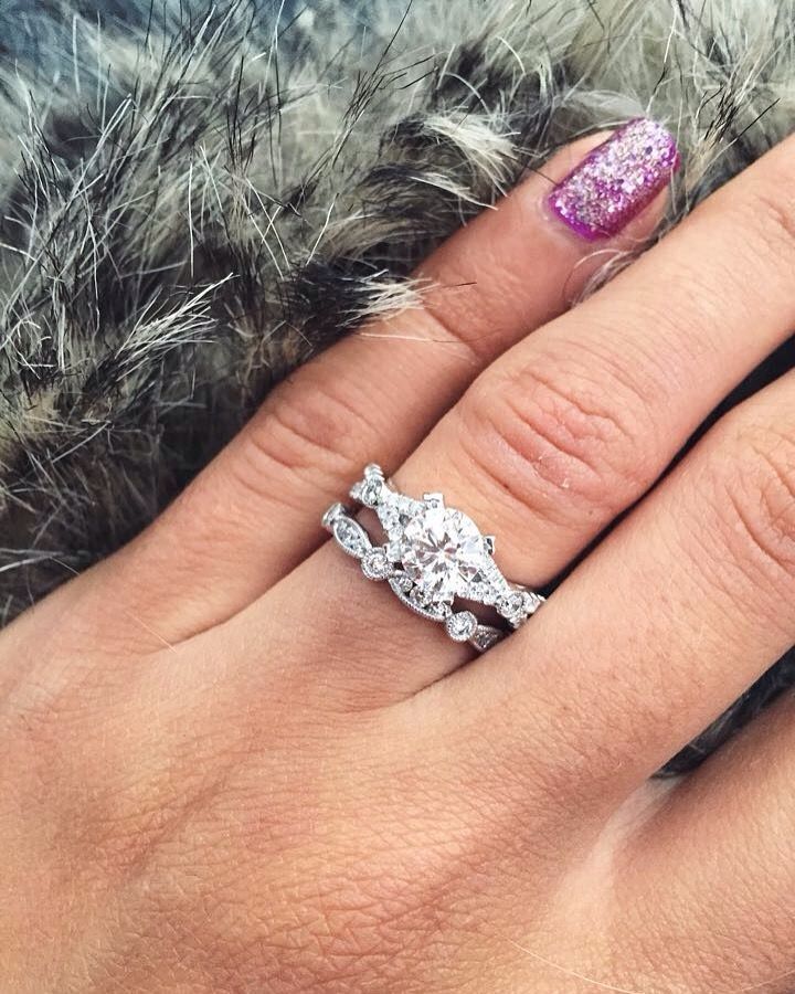 A woman 's hand with a wedding ring and engagement ring on it