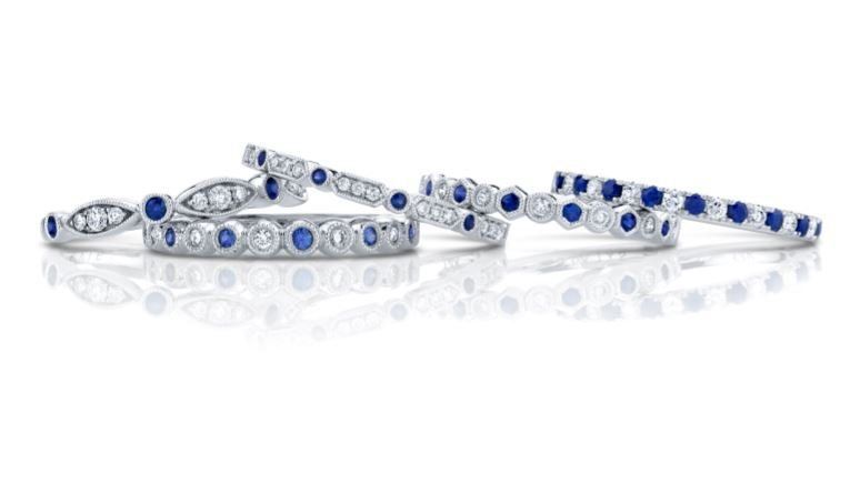 A row of sapphire and diamond rings on a white surface.