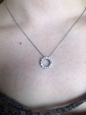 A woman wearing a necklace with a circle shaped pendant