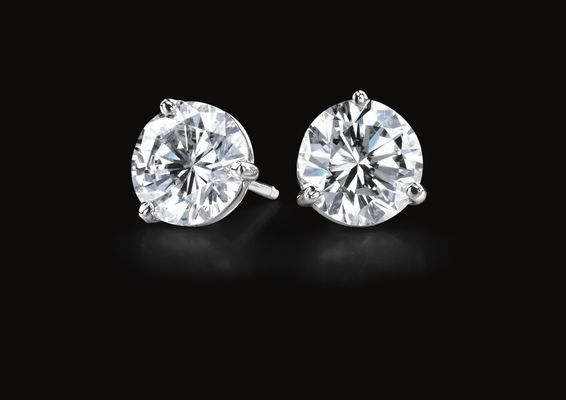 A pair of diamond stud earrings on a black background.
