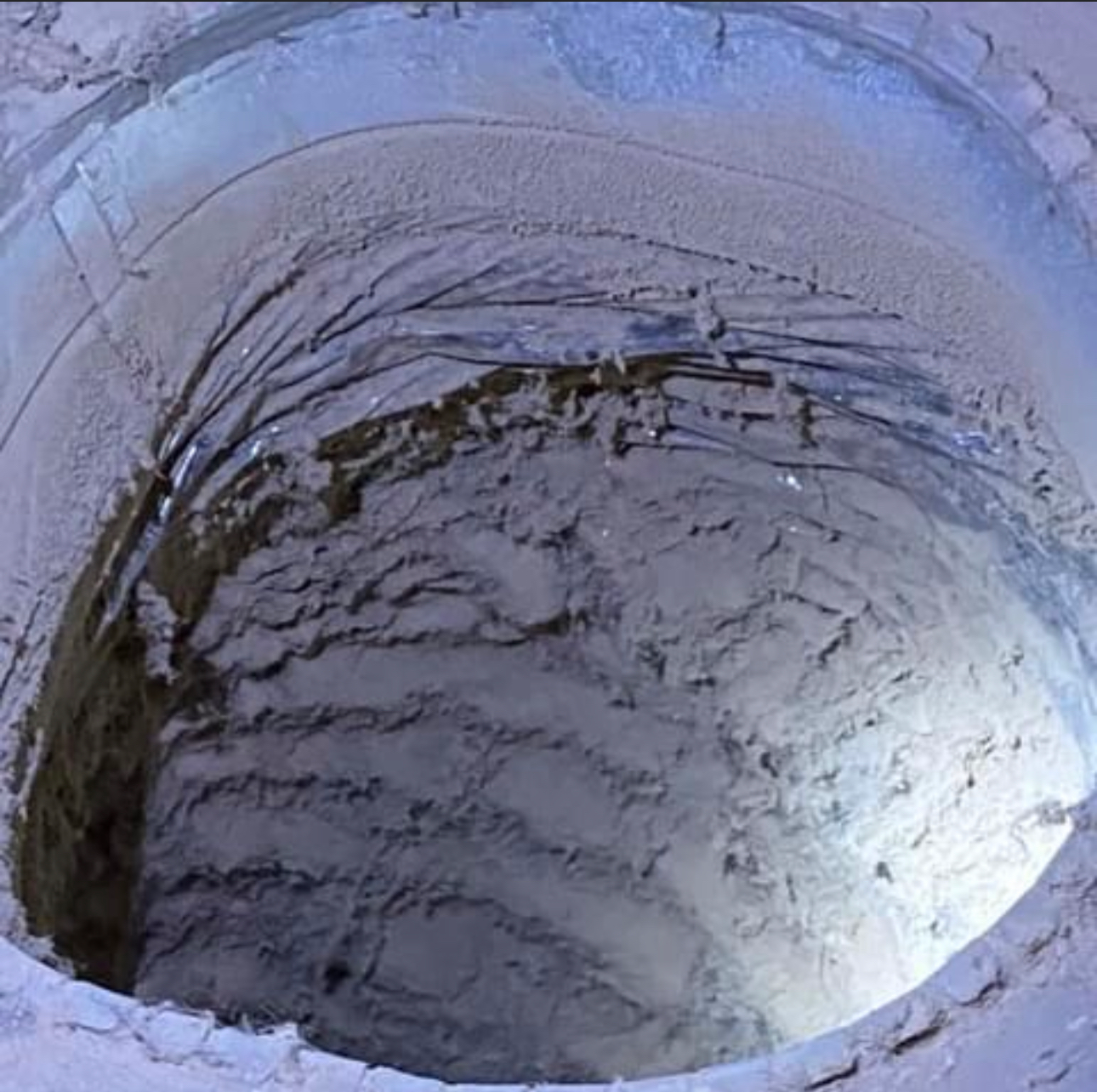 A hole in the ground with a light shining through it