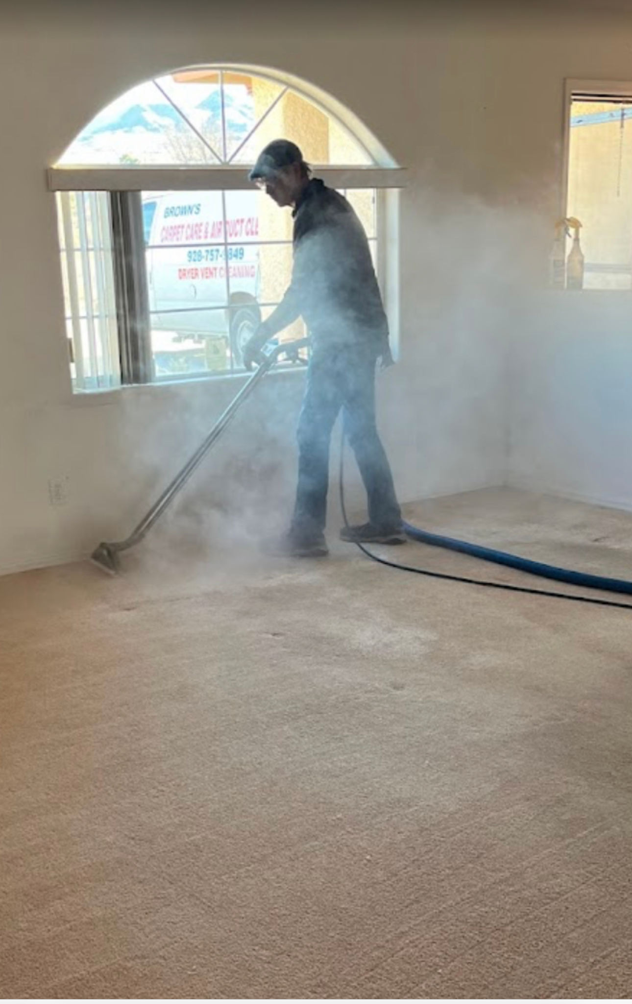 A man is cleaning a carpet with a vacuum cleaner in a living room.