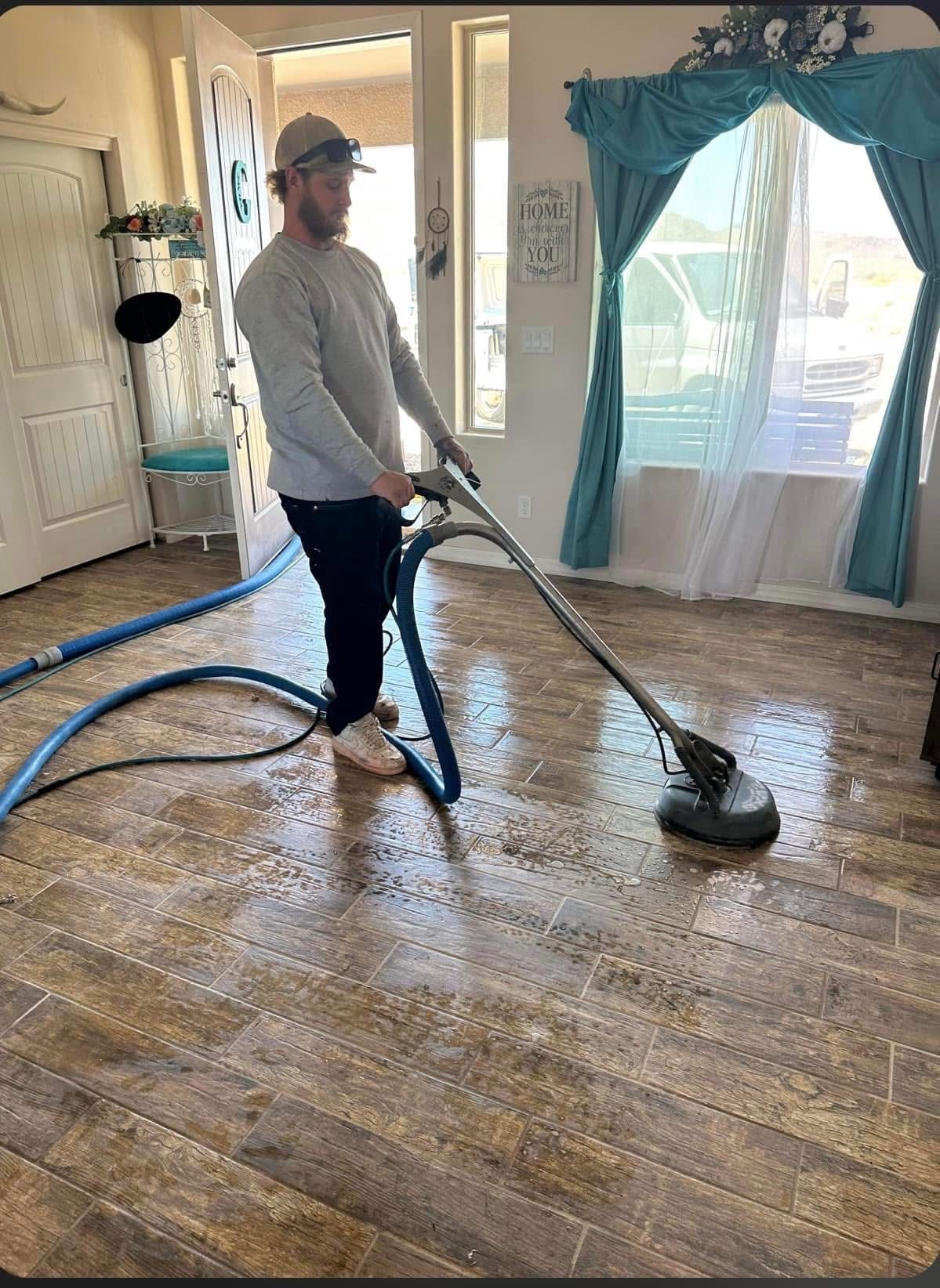A man is cleaning a wooden floor with a vacuum cleaner.