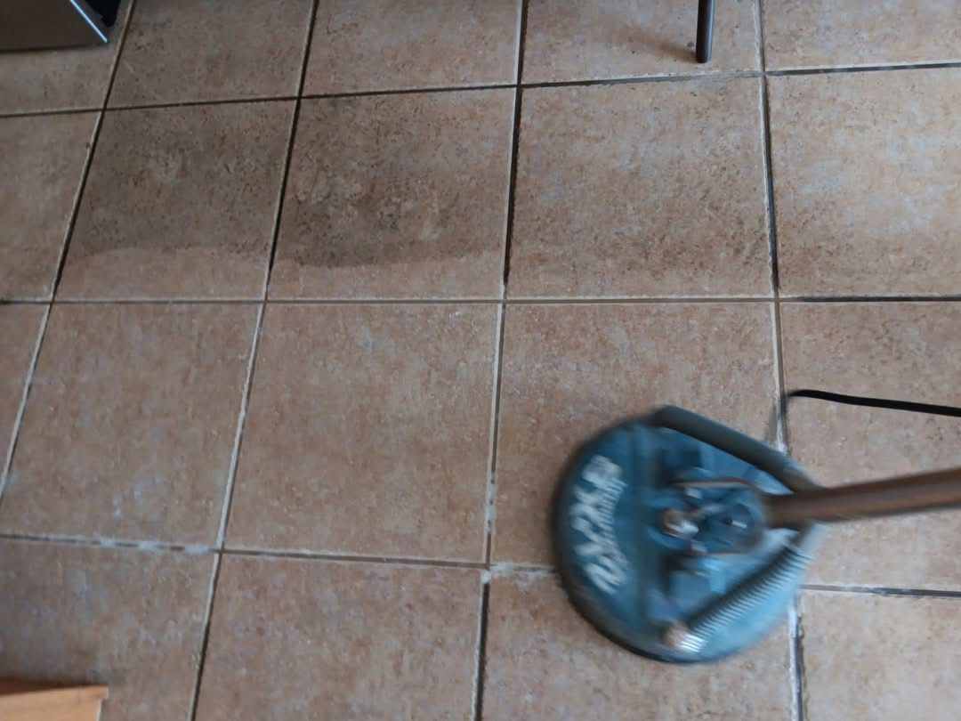 A mop is sitting on a tiled floor next to a chair