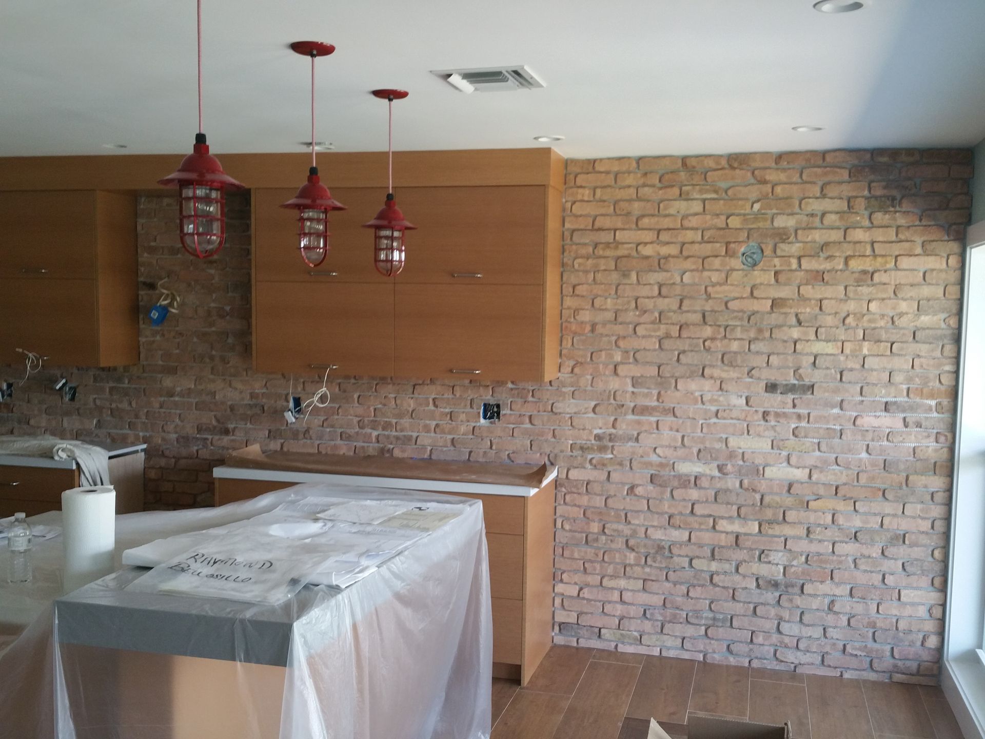 Modern recessed lighting and custom red pendant lights in brick accent kitchen
