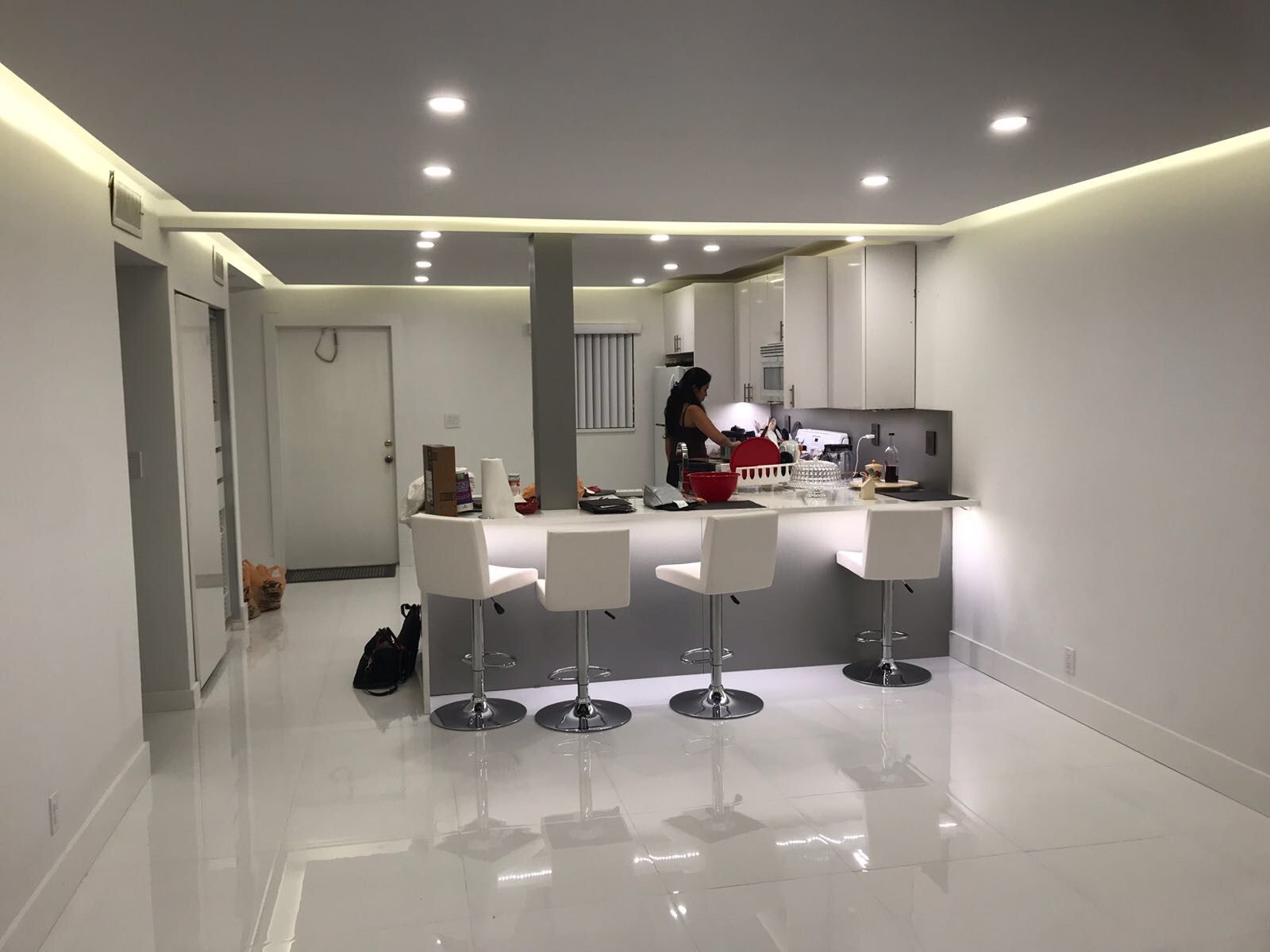 Recessed lighting and under-cabinet illumination in sleek white kitchen renovation