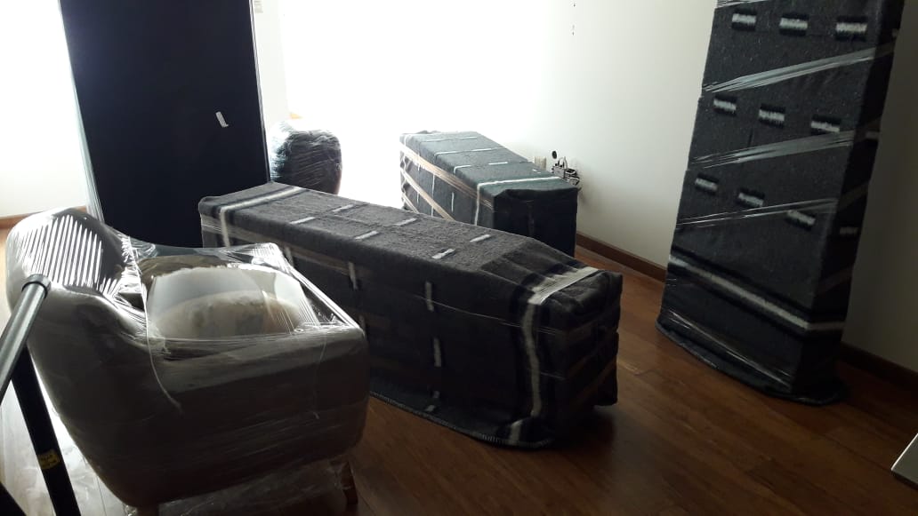 Una sala llena de muebles y cajas envueltas en plástico.