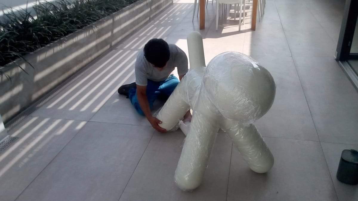 Un hombre está arrodillado en el suelo junto a un animal de peluche.