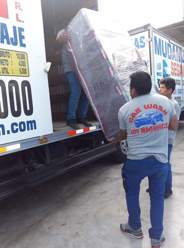 Un hombre lleva un colchón a un camión de mudanzas