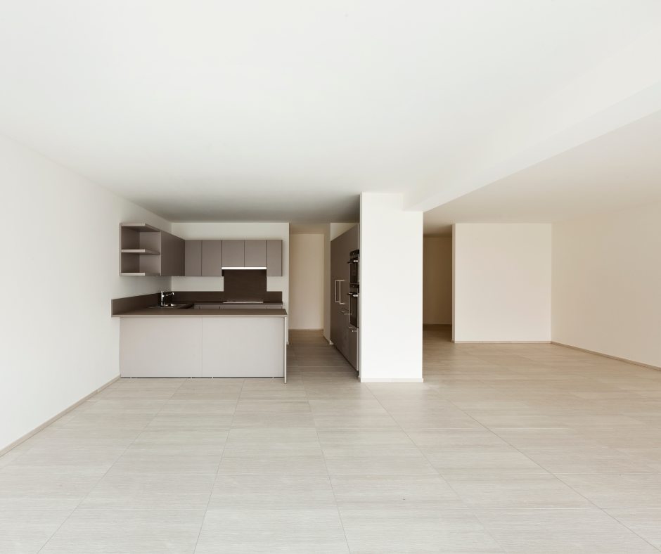 Appartement moderne vide avec cuisine équipée de placards gris. Sol gris clair et murs blancs.