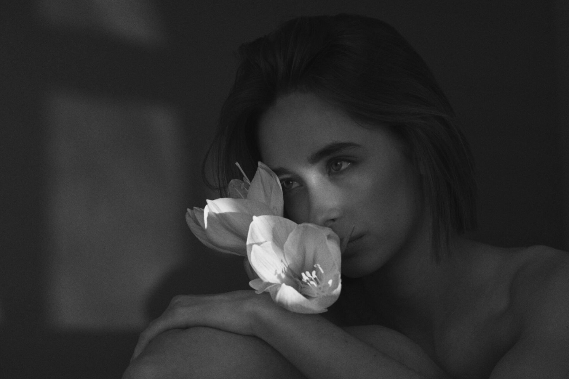 Eine Frau mit Blumen in der Nähe ihres Gesichts, in Schwarzweiß.