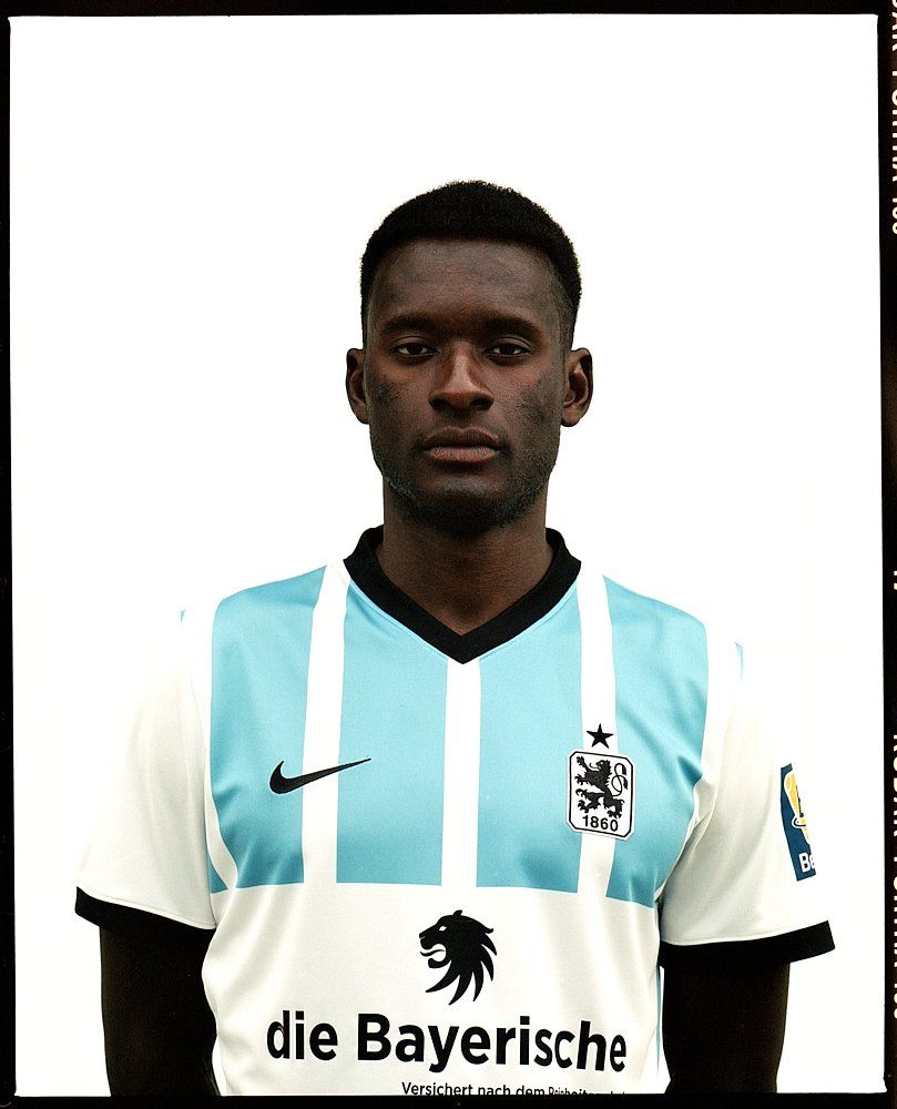 Fußballspieler in einem hellblau-weißen Trikot, ernster Gesichtsausdruck, weißer Hintergrund.