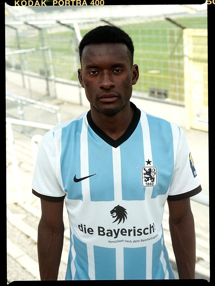 Fußballspieler im blau-weißen Trikot steht vor einem Stadion.