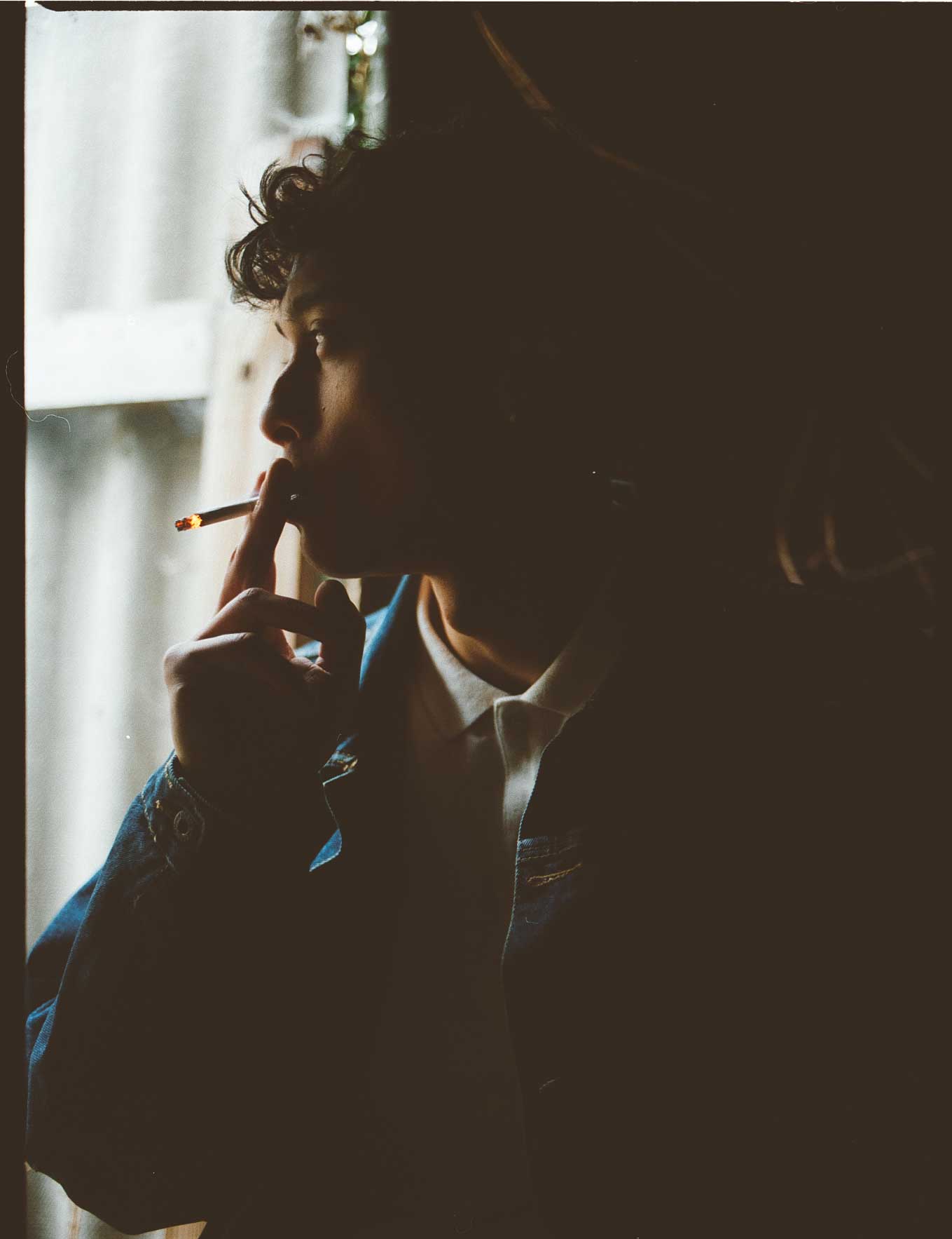 Person, die an einem Fenster eine Zigarette raucht, Silhouette.