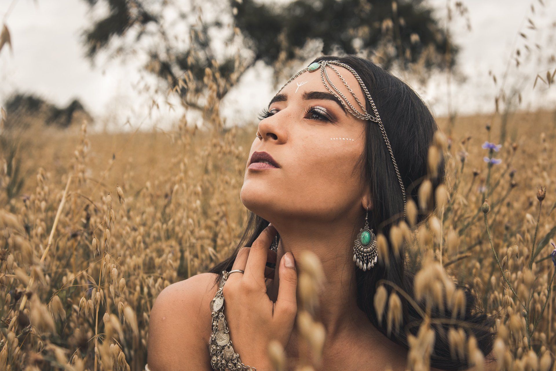 Frau mit Kopfbedeckung im Weizenfeld, Blick nach oben.