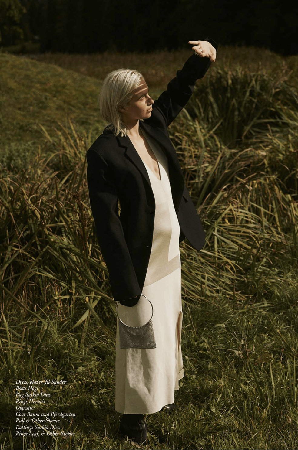 Person in schwarzem Blazer und weißem Kleid, die ihre Augen im Feld abschirmt.