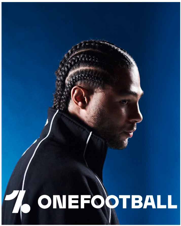 Mann mit geflochtenen Haaren in schwarzer Jacke, Profilansicht, mit blauem Hintergrund. OneFootball-Logo.