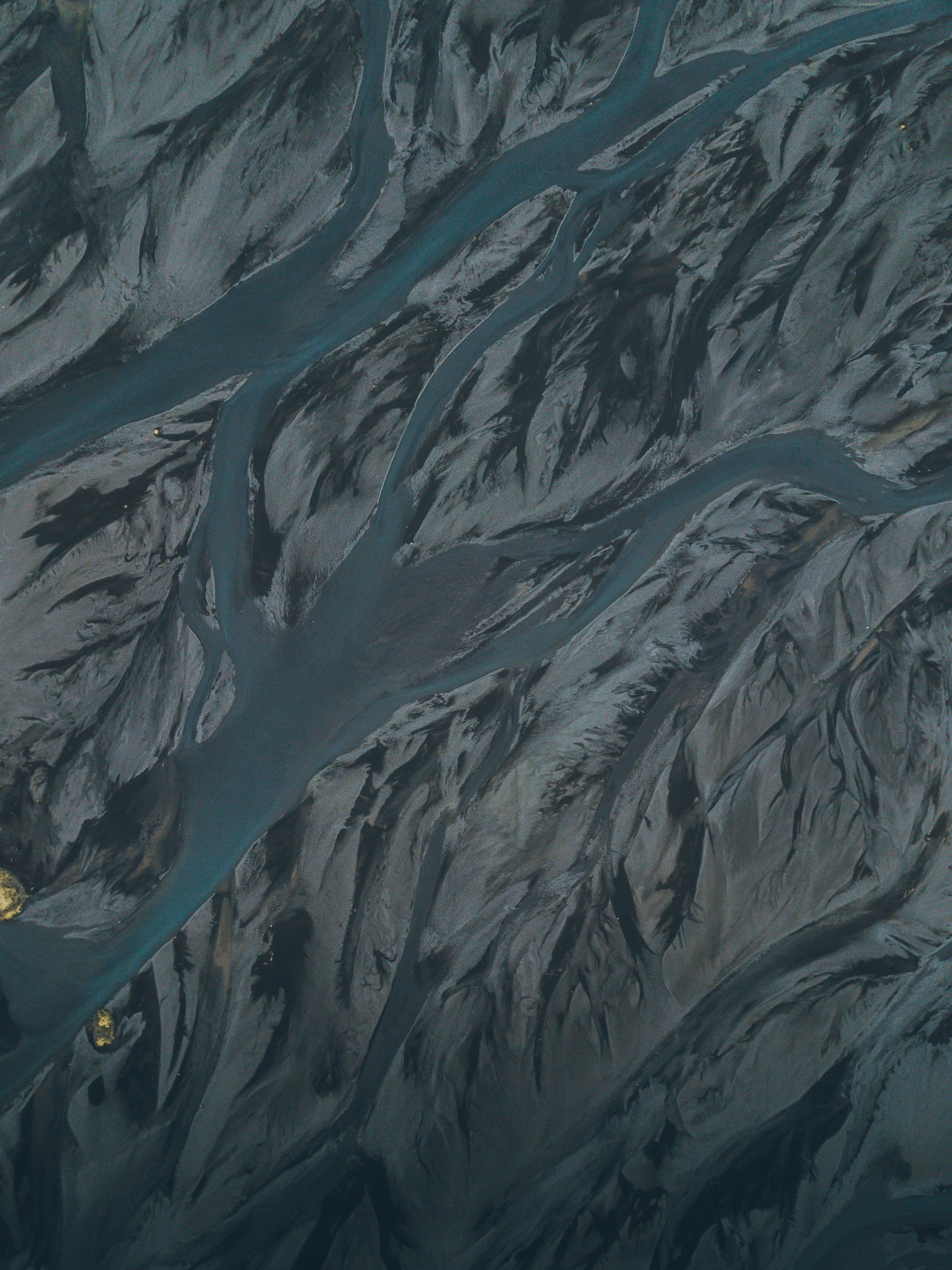 Verzweigtes Flusssystem, blaugrünes Wasser, schwarzer Sand. Luftaufnahme.