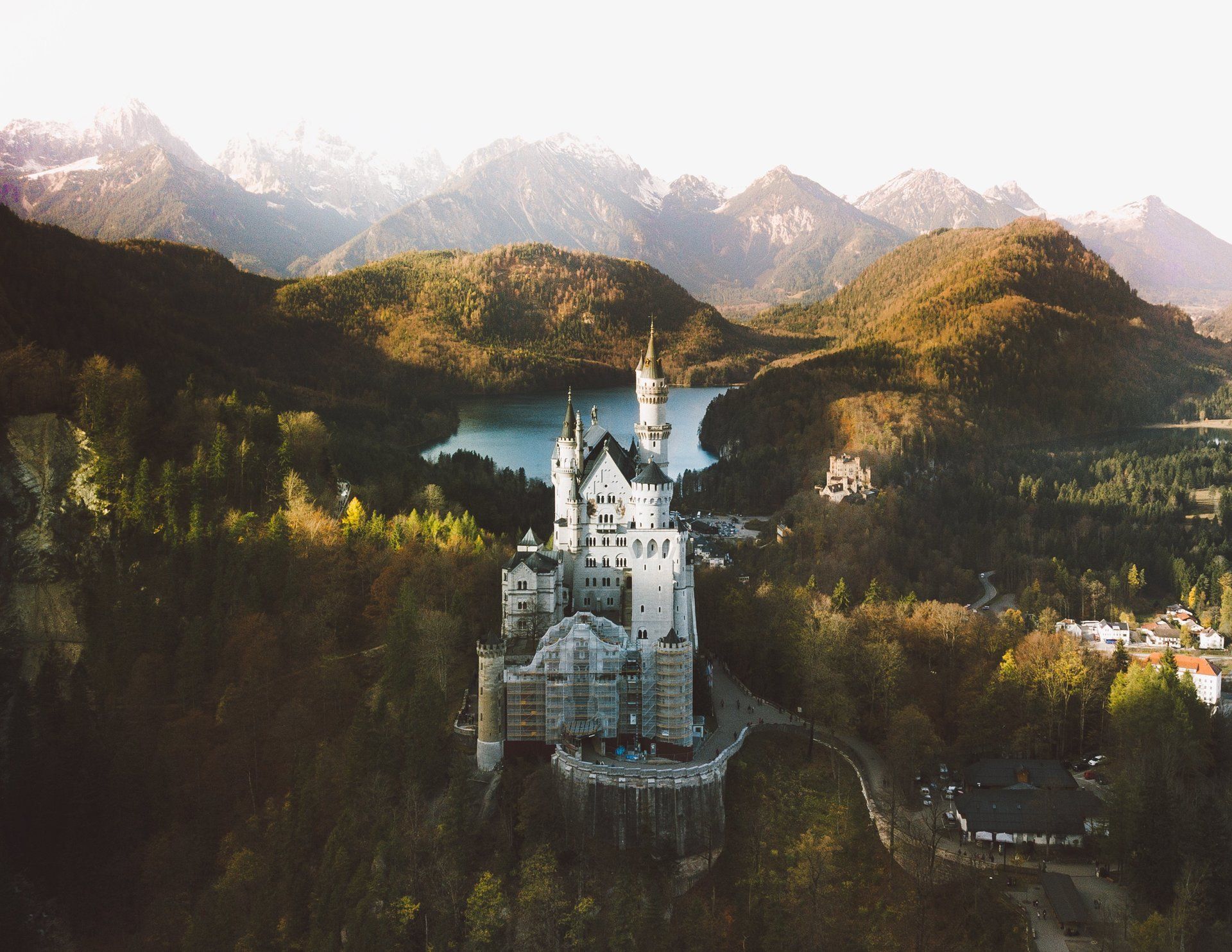 Schloss Neuschwanstein in Deutschland, ein weißes Märchenschloss auf einem Hügel, umgeben von Bergen und einem See.