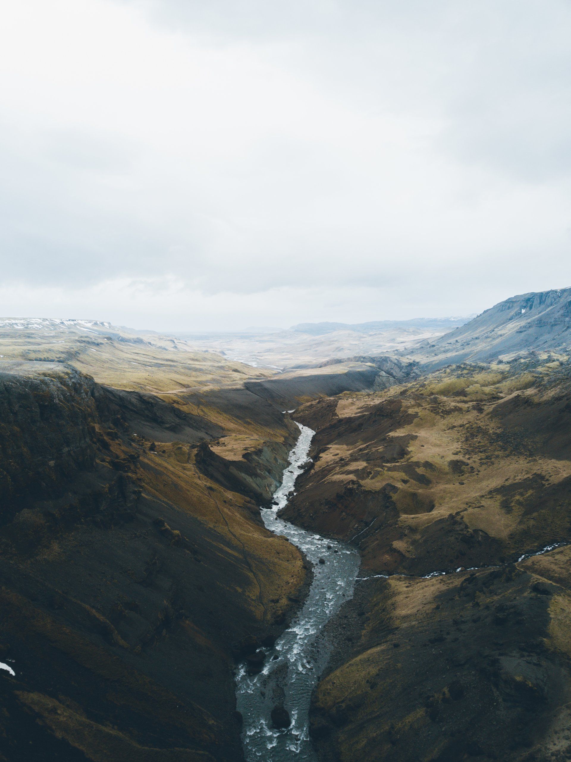 Ein gewundener Fluss schlängelt sich unter einem bewölkten Himmel durch eine Schlucht.
