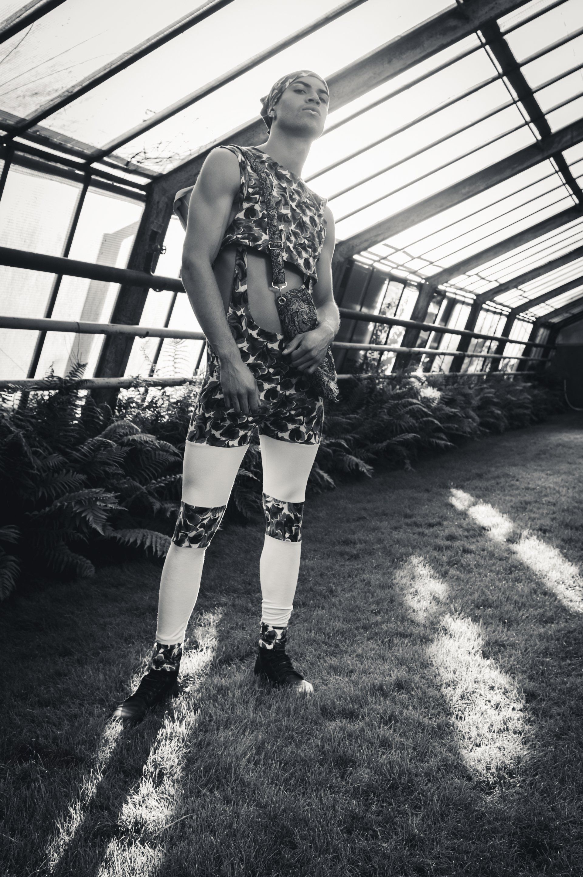 Mann in Tarnkleidung und Leggings posiert in einem Gewächshaus.