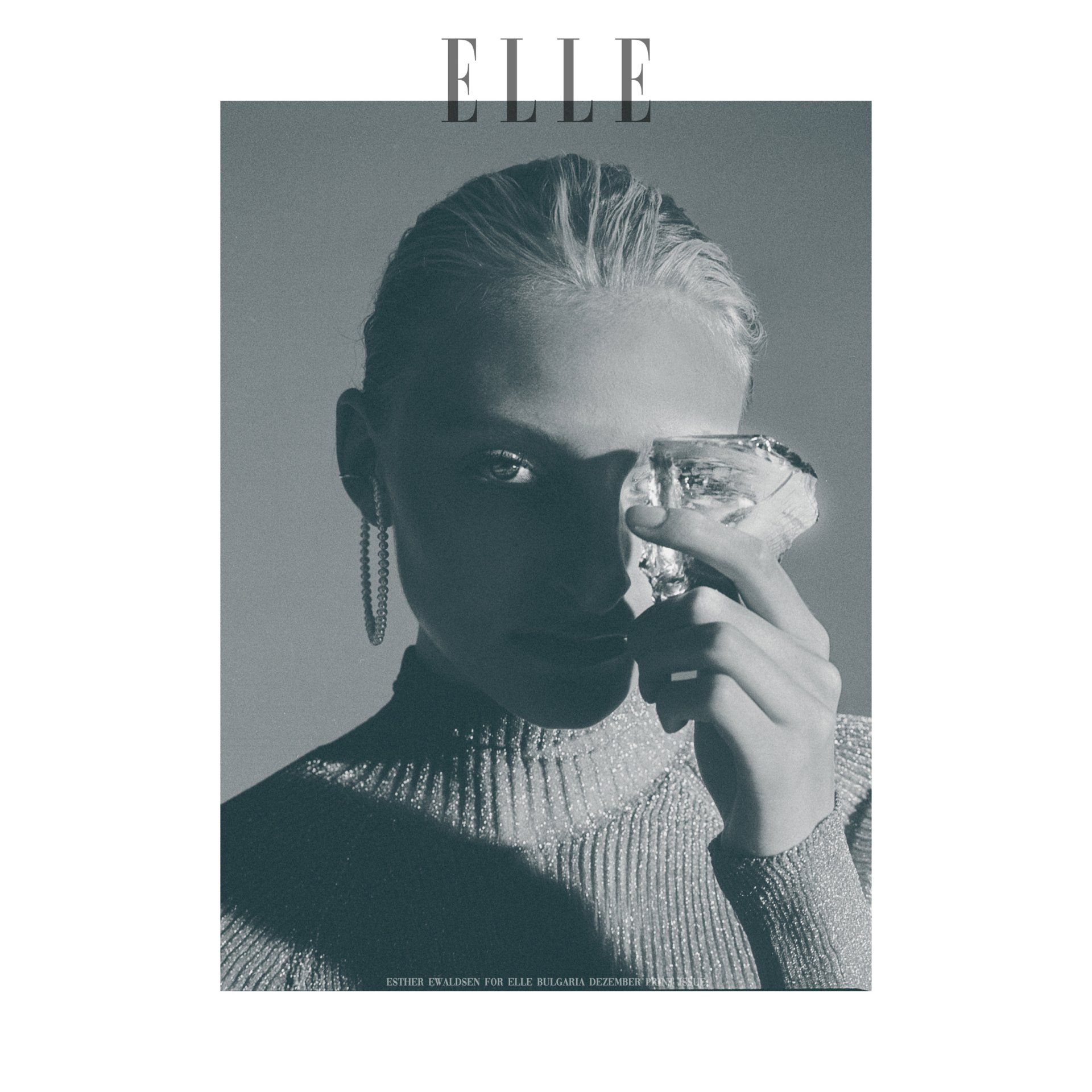 Frau hält einen Kristall über einem Auge, für das ELLE-Magazin. Schwarzweißfoto, glitzerndes Oberteil und Ohrringe.