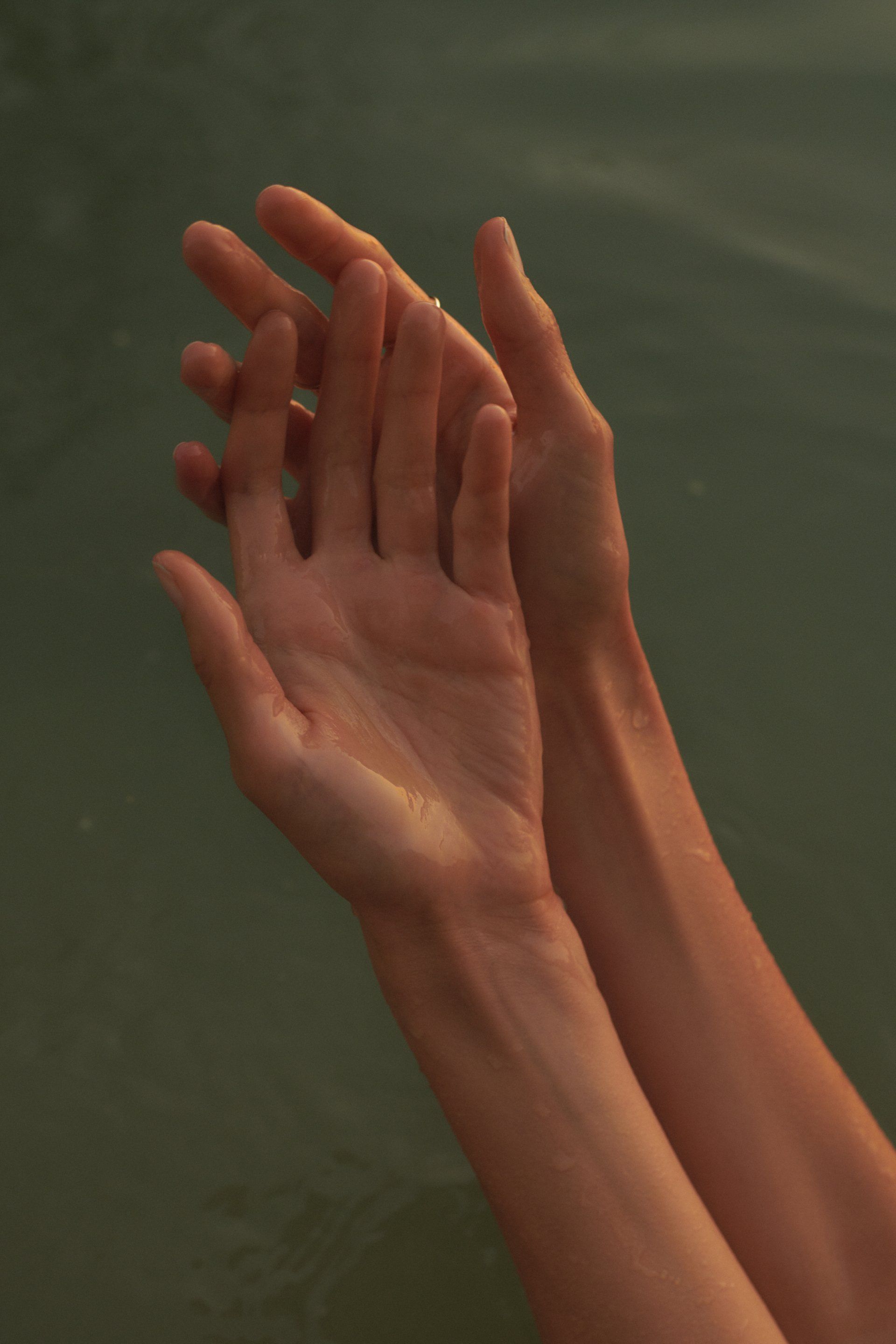 Zwei blasse Hände ragen aus dem Wasser.