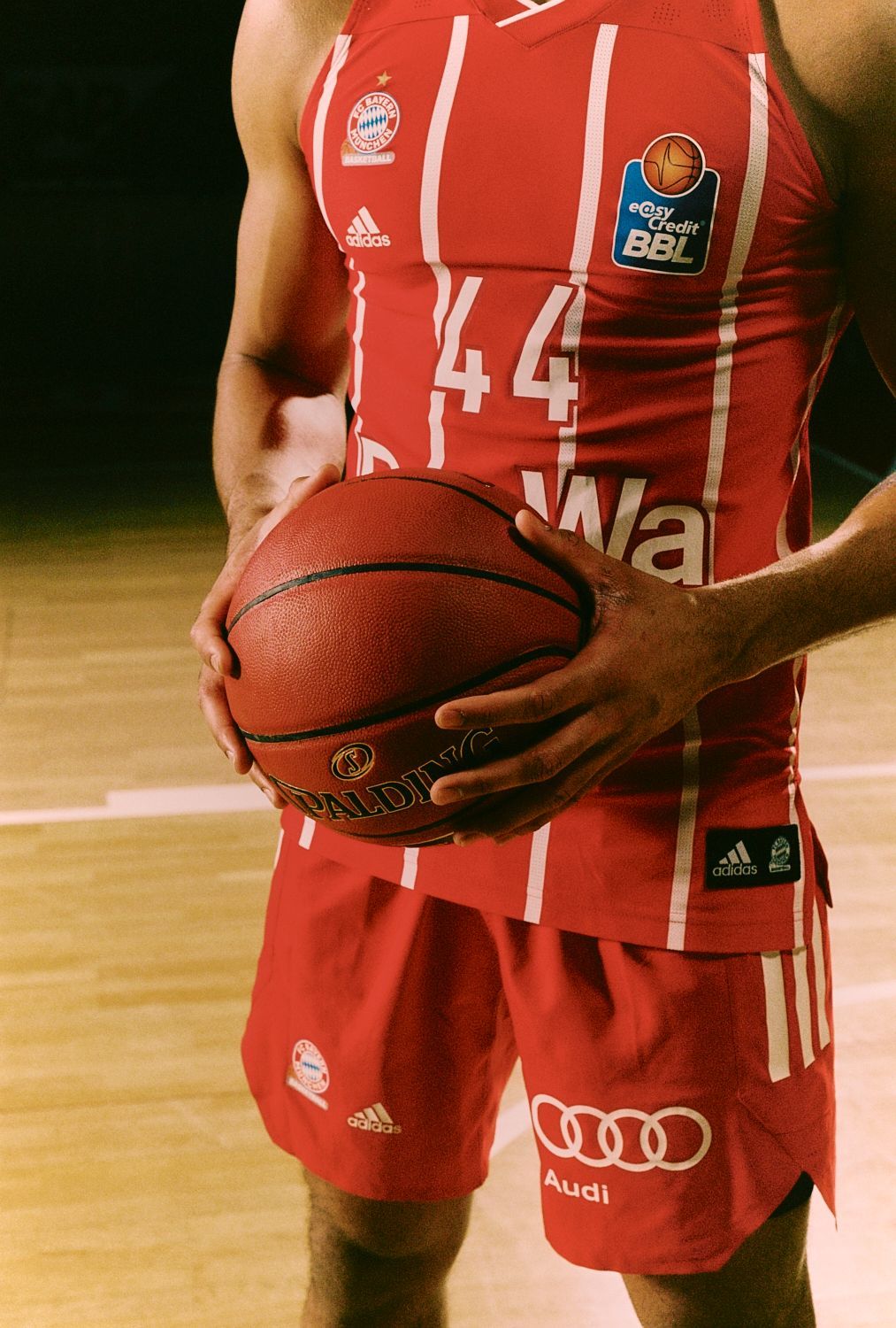 Basketballspieler in roter Uniform hält einen Basketball.