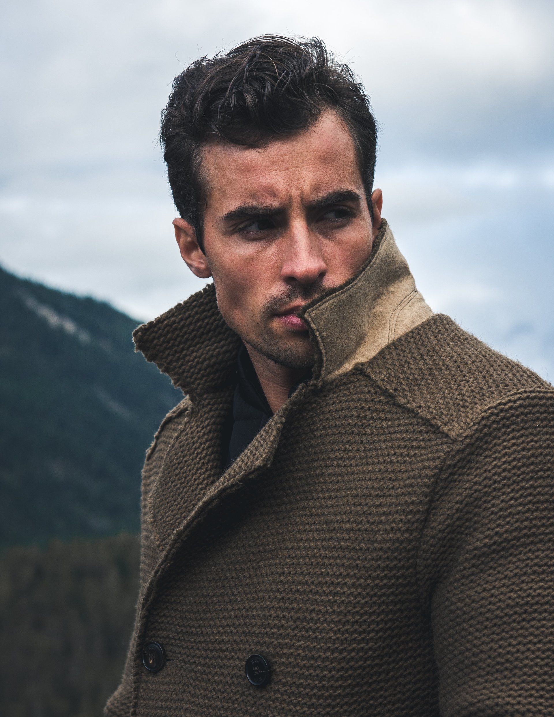 Mann im braunen Mantel, Bergkulisse.