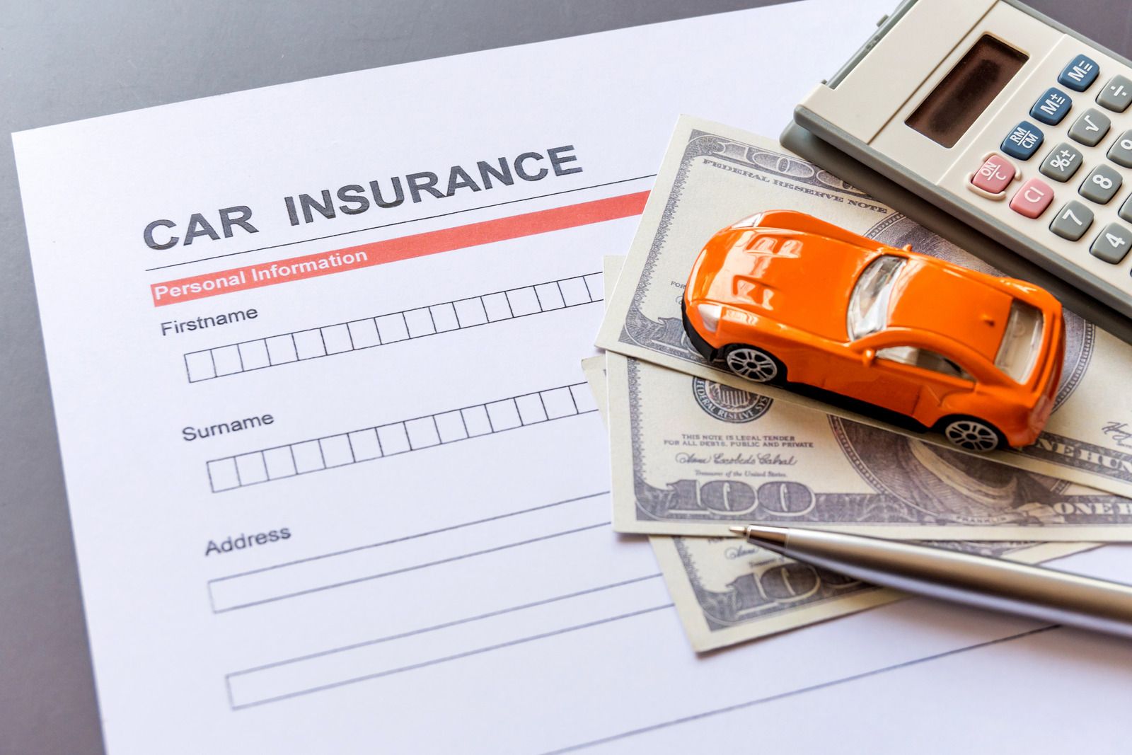A toy car is sitting on top of a car insurance form.