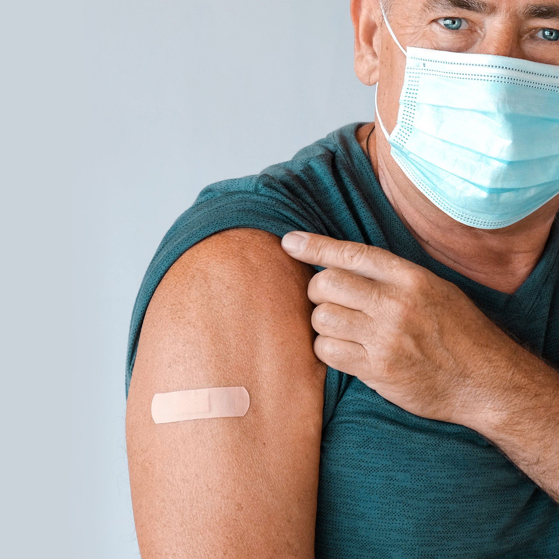 Ein Mann mit einer Maske hat einen Verband am Arm.