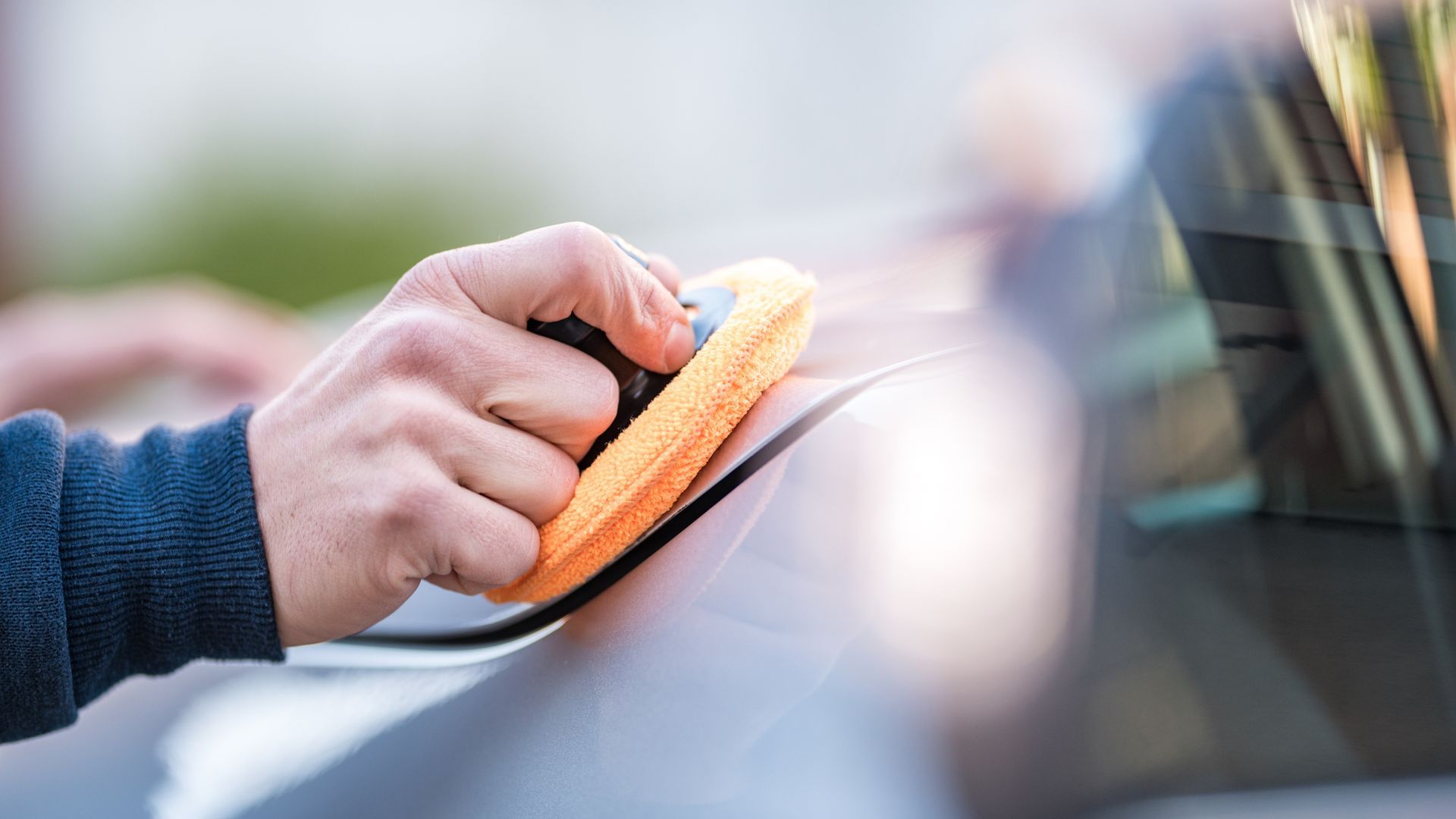 A person is cleaning a car with a sponge.