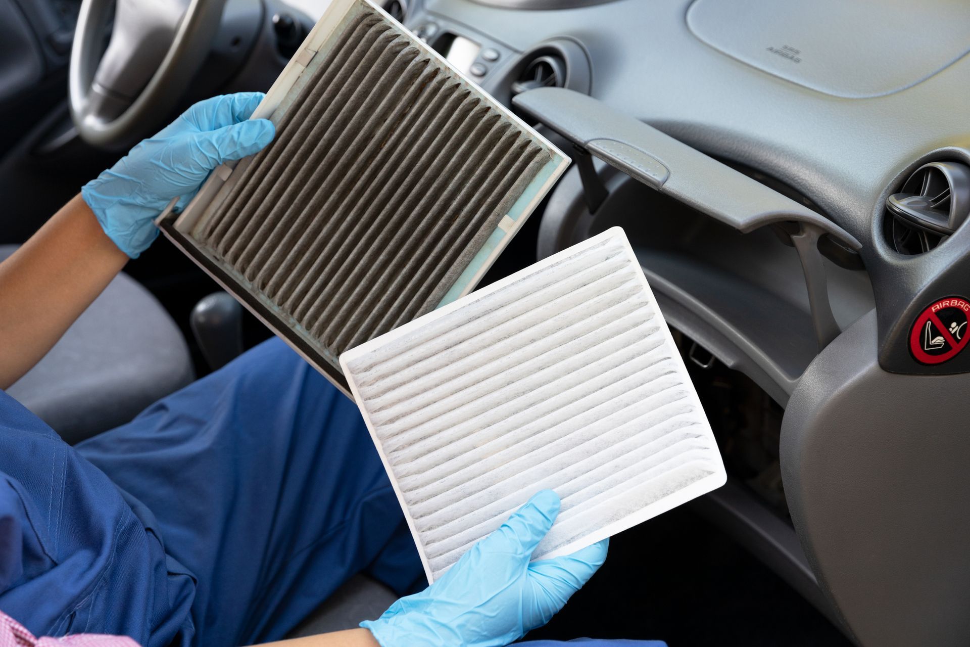A person is holding two air filters in their hands in a car.