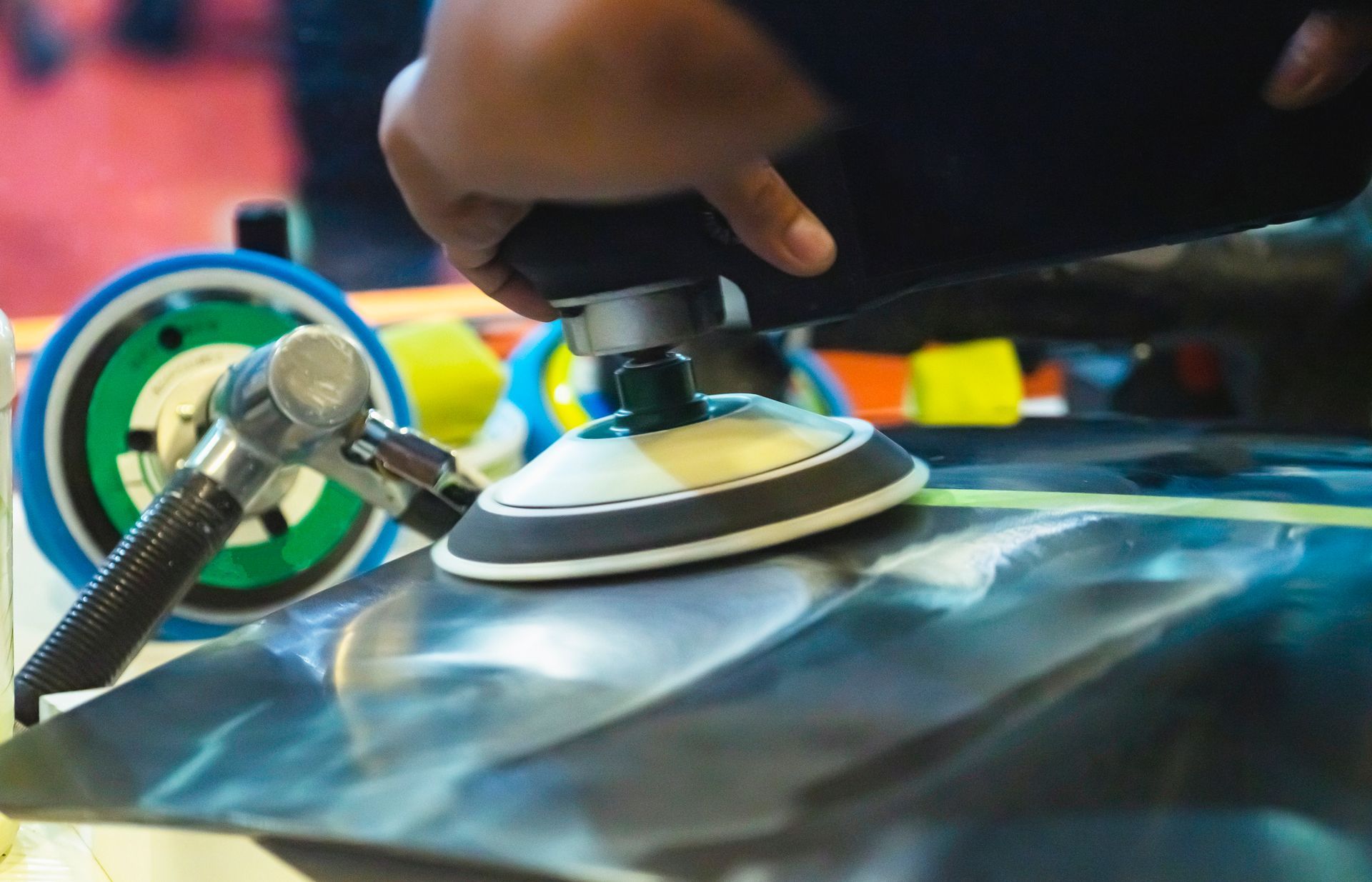 A person is polishing a car with a sander.