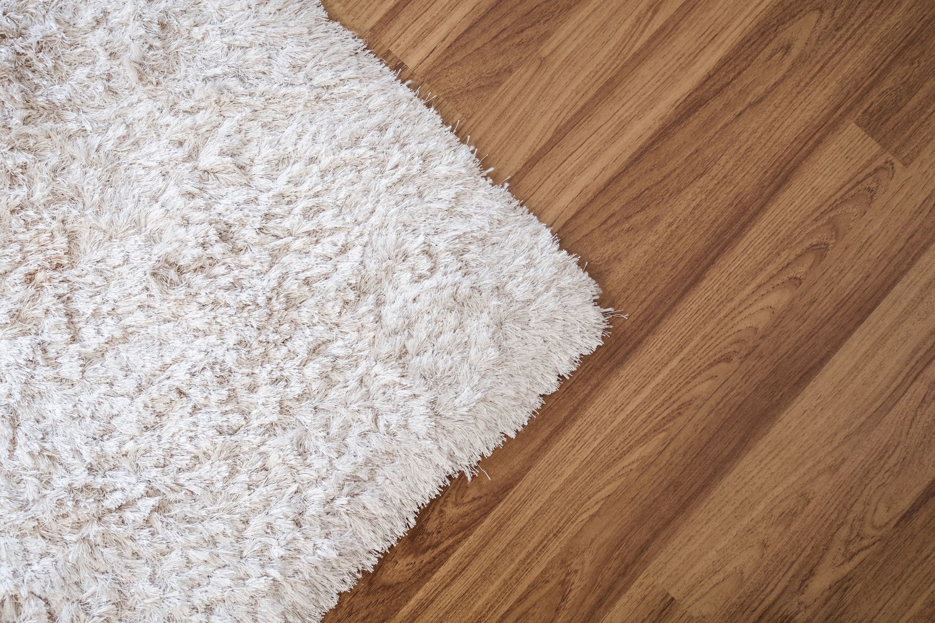 A white rug is sitting on a wooden floor.