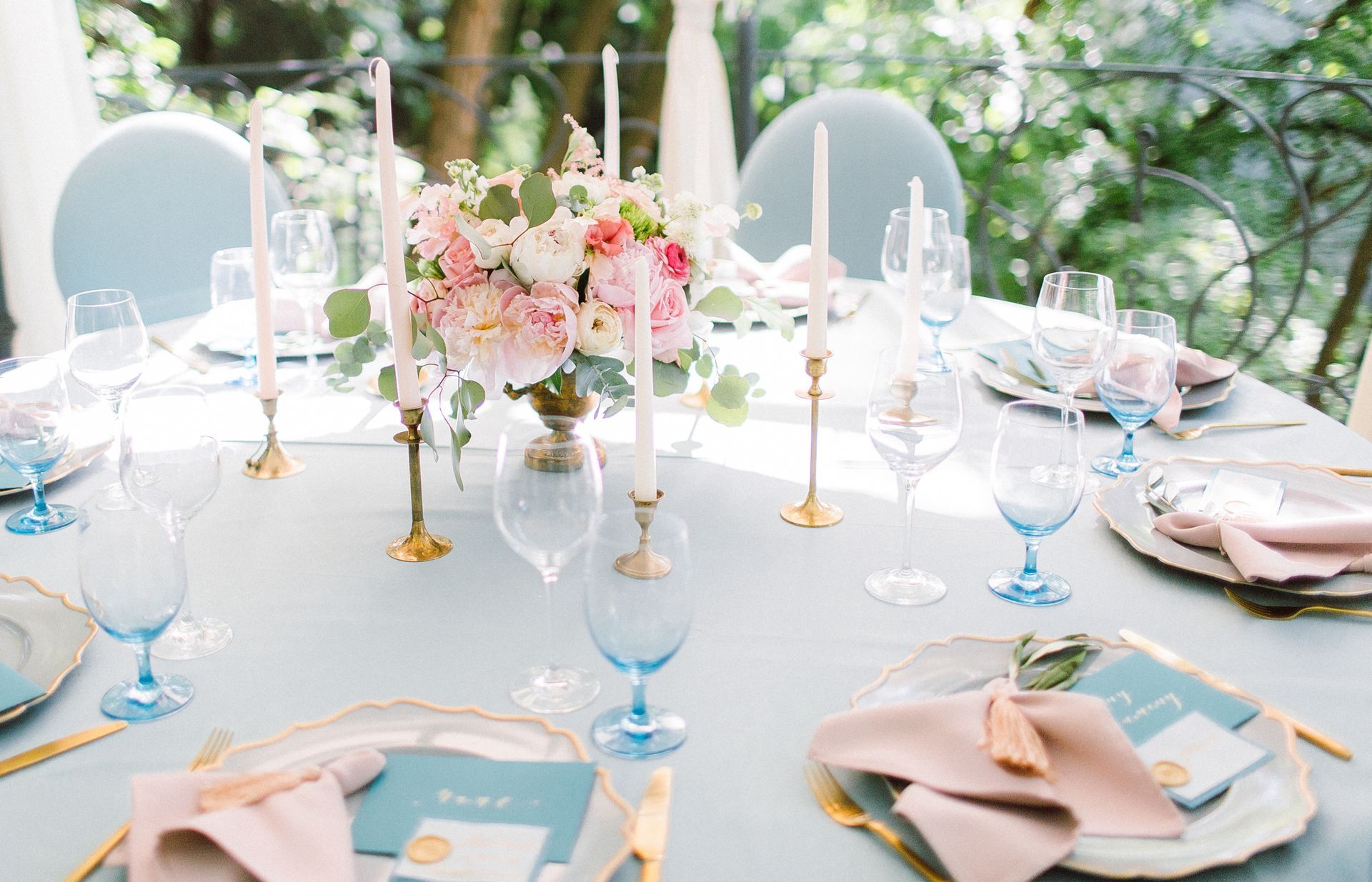 A table set for a wedding reception with plates , glasses , napkins and candles.