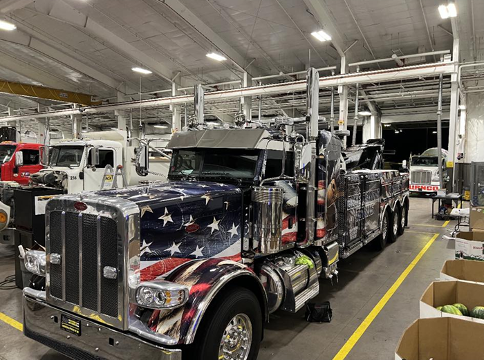 A semi-truck with an American flag wrap is inside a warehouse.
