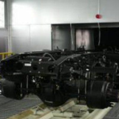 Un vehículo negro está estacionado sobre una plataforma de madera en una habitación.