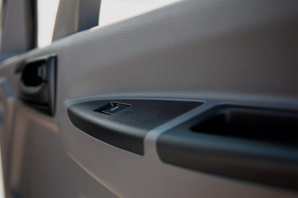 Un primer plano de una puerta de automóvil con una manija negra.