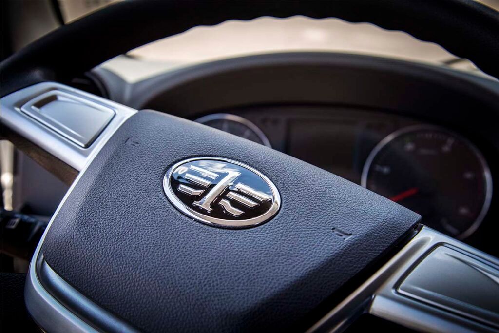 Un primer plano del volante de un automóvil con un logotipo en él.