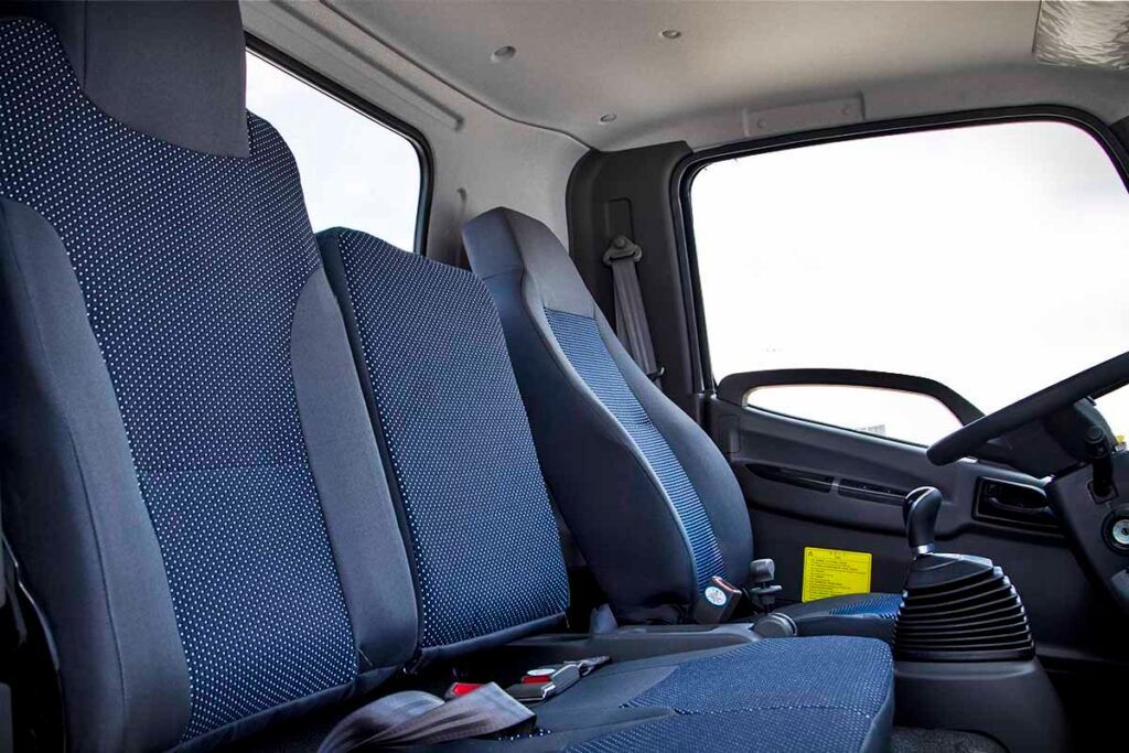 El interior de un camión con asientos azules y un volante.