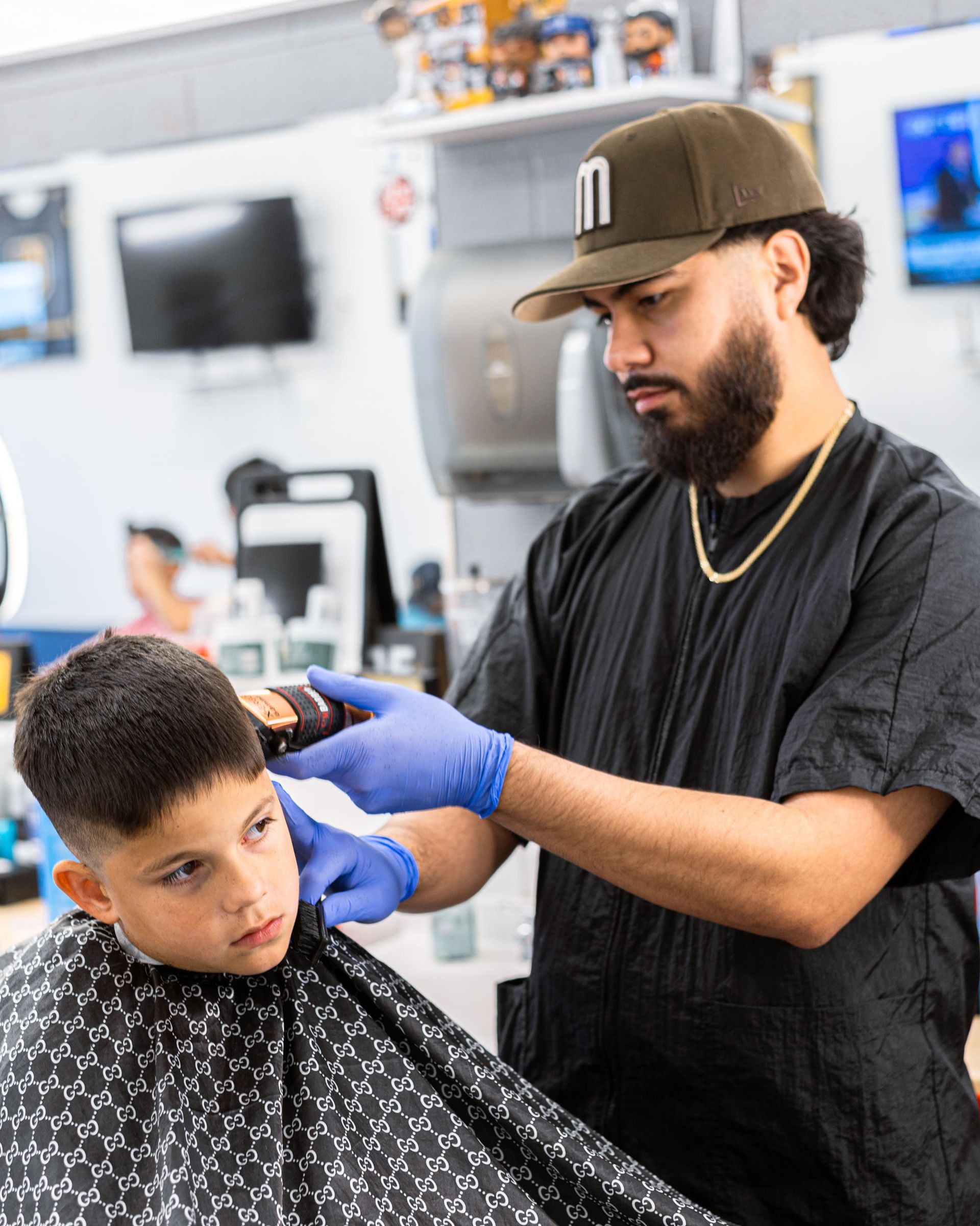 Barber in black shirt and cap cutting a client’s hair in a barbershop