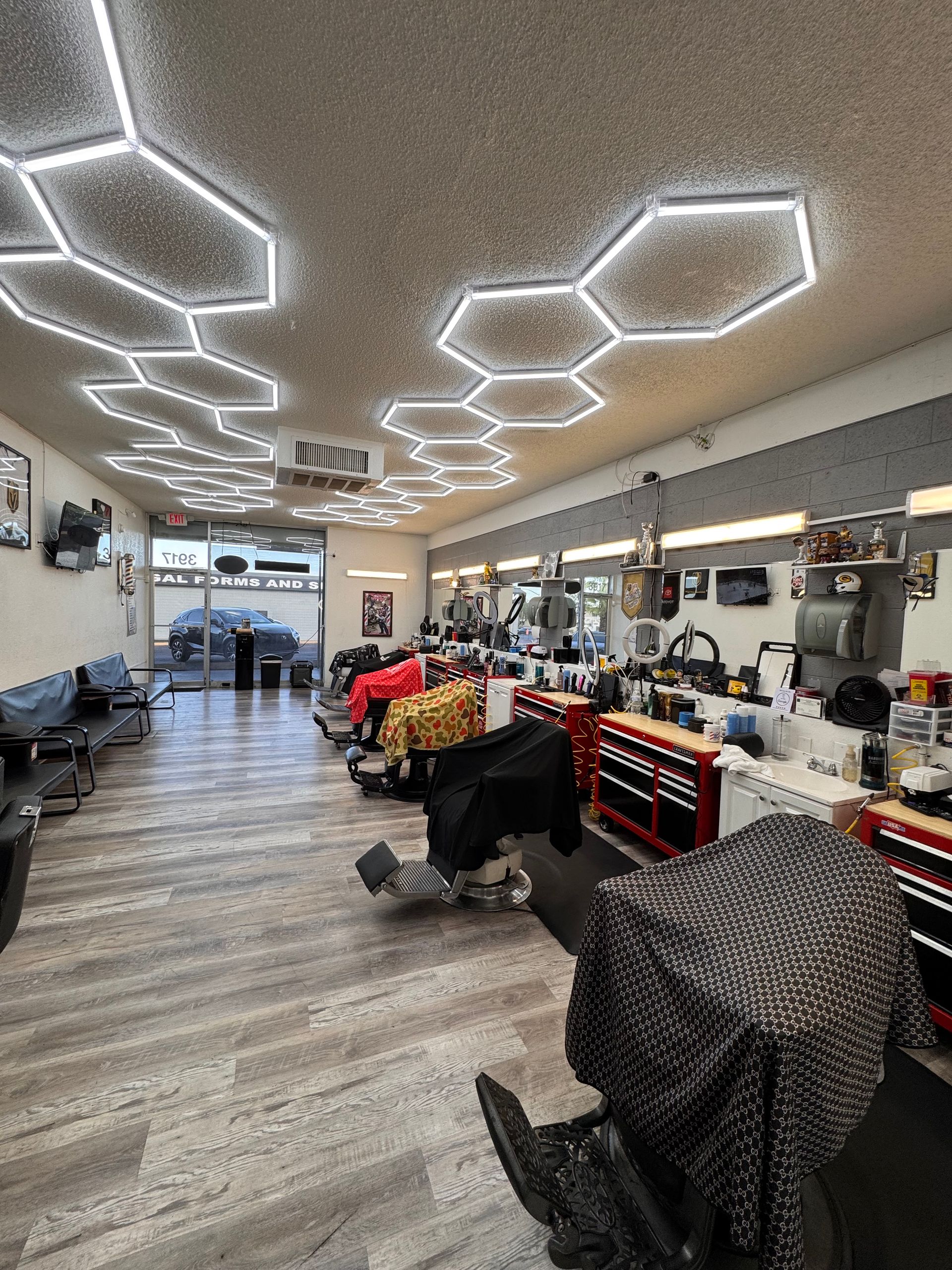 Bright salon interior with hexagon ceiling lights, styling chairs, mirrors, and red tool carts along the wall