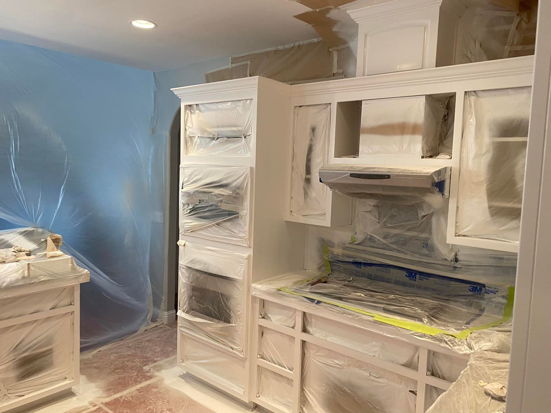 White kitchen cabinets with gray countertops, stainless steel dishwasher, and a window.